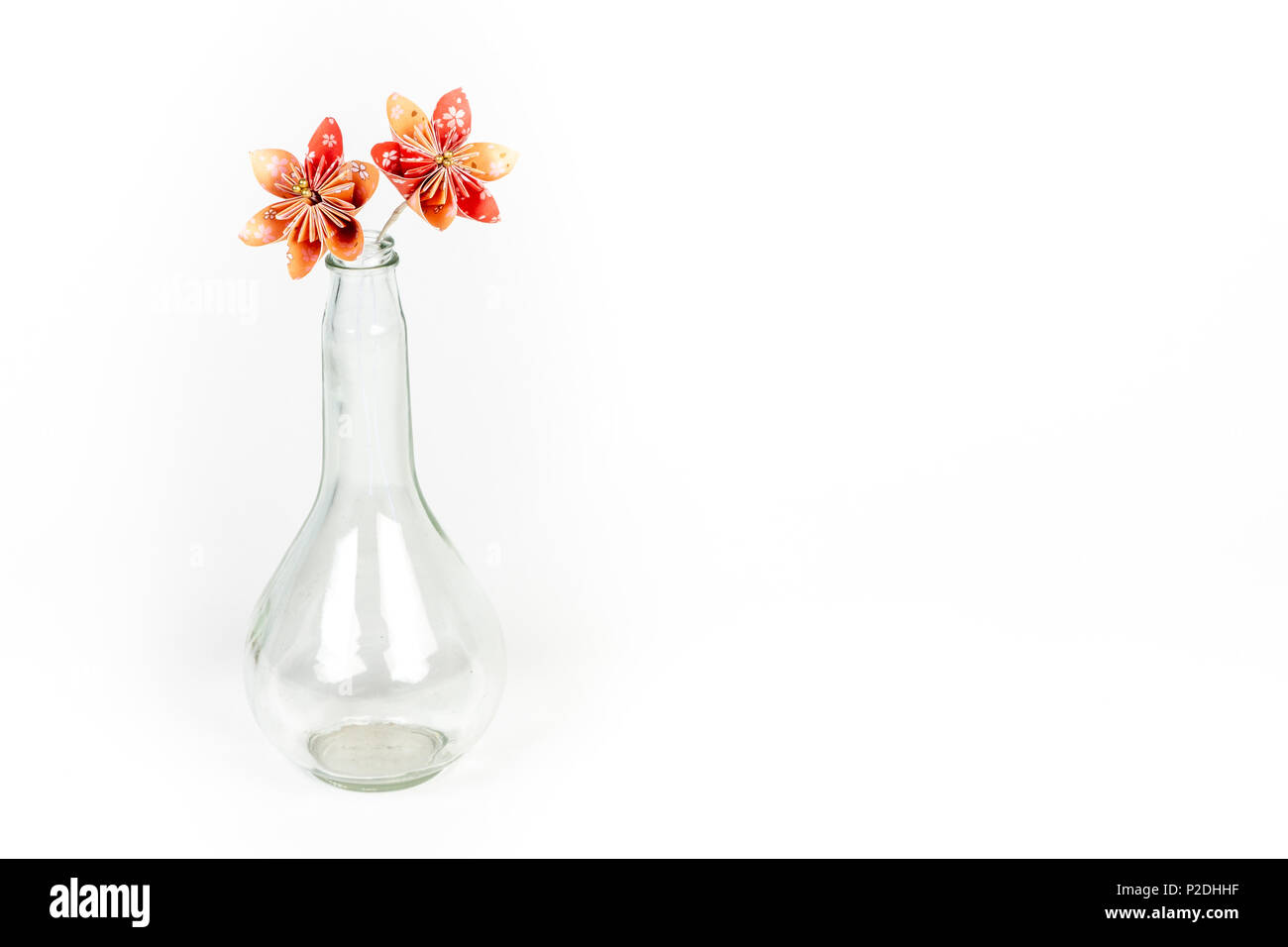 Due orange origami fiori in vetro trasparente bottiglia su sfondo bianco. Foto Stock