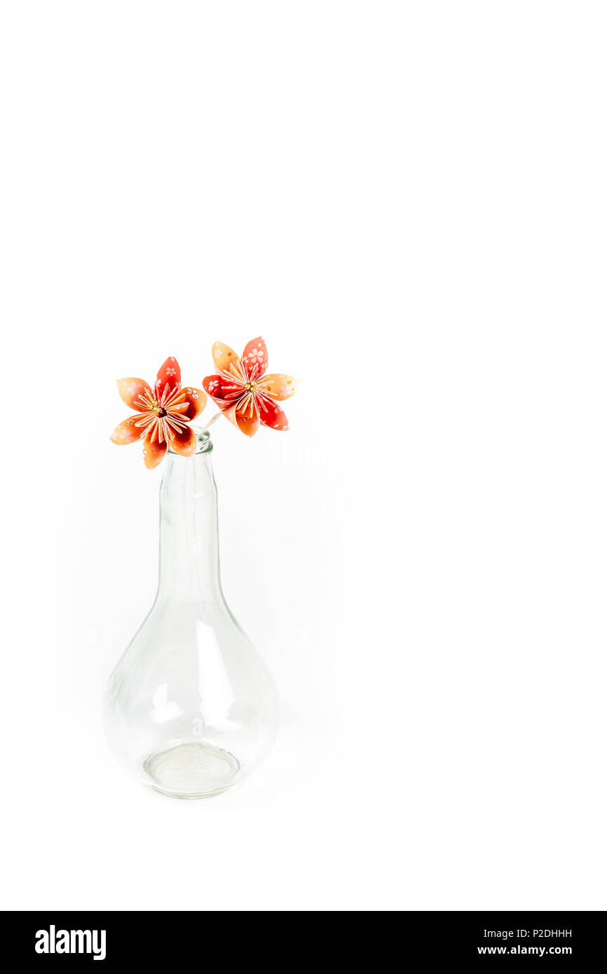 Due orange origami fiori in vetro trasparente bottiglia su sfondo bianco. Foto Stock