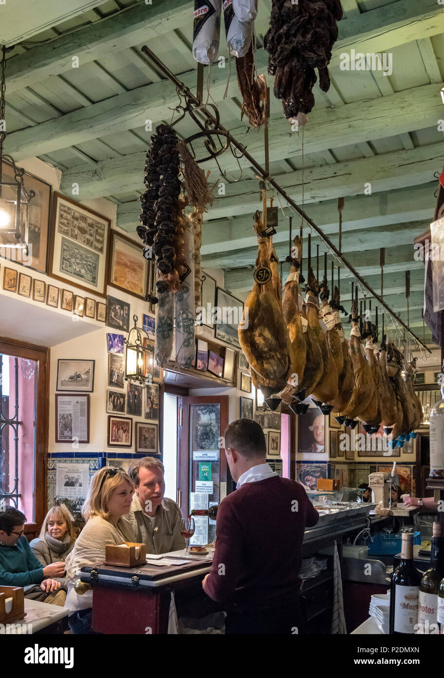 Il tapas bar, Siviglia, Spagna. Barman servire il vino ad una coppia in un bar di tapas nel Barrio Santa Cruz, Sevilla, Andalusia, Spagna Foto Stock