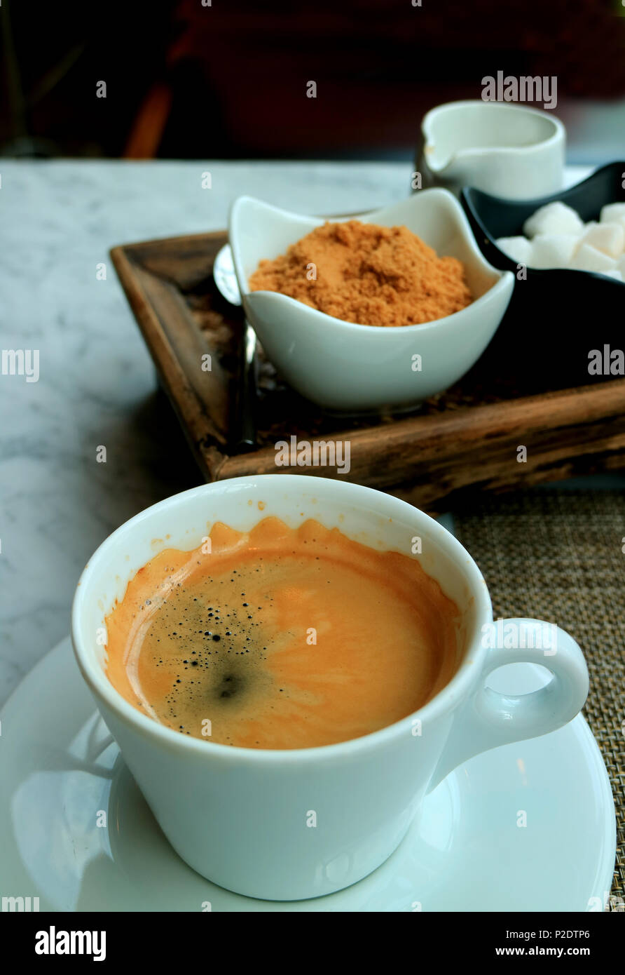 Una tazza di acqua calda Americano servita al tavolo con un condimento di caffè impostata Foto Stock