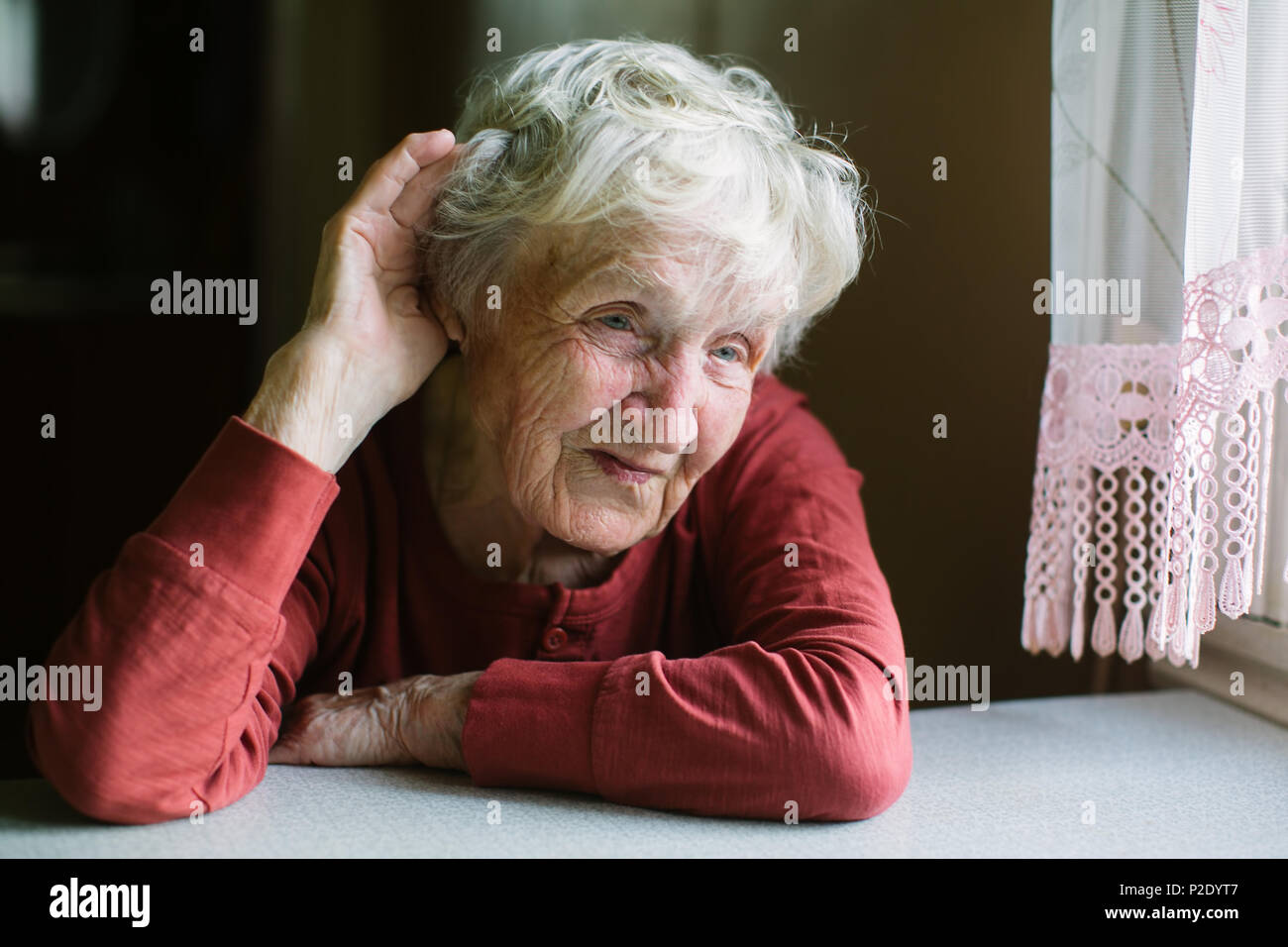 Una donna anziana ascolta con la sua mano al suo orecchio. Problemi di udito, seniors perdita di udito. Foto Stock
