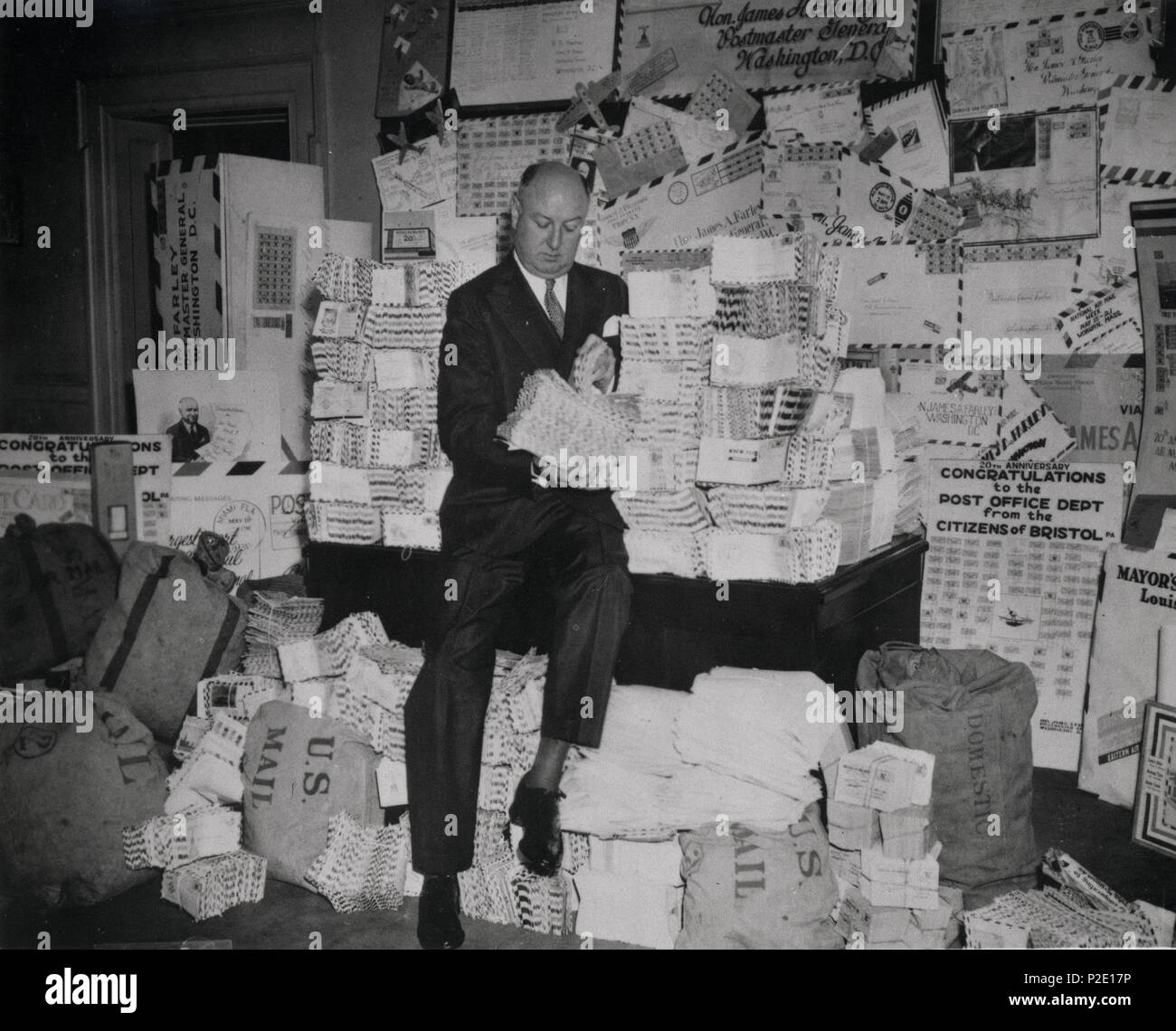 . Descrizione: Postmaster Generale James A. Farley è mostrato seduto con alcune delle centinaia di migliaia di lettere spedite durante il National Air Mail settimana maggio 15-21, 1938. La celebrazione nazionale onorato il ventesimo anniversario del primo pianificate regolarmente il servizio di posta aerea. Il presidente Franklin Roosevelt e il suo generale Postmaster incoraggiato tutti a inviare una lettera di posta aerea durante la settimana di eventi. Creatore/Fotografo: fotografo non identificato di medie: stampa fotografica in bianco e nero di cultura: la geografia americana: STATI UNITI D'America Data: 1938 collezione: U.S. Servizio di posta aerea Repository: National Posta Foto Stock