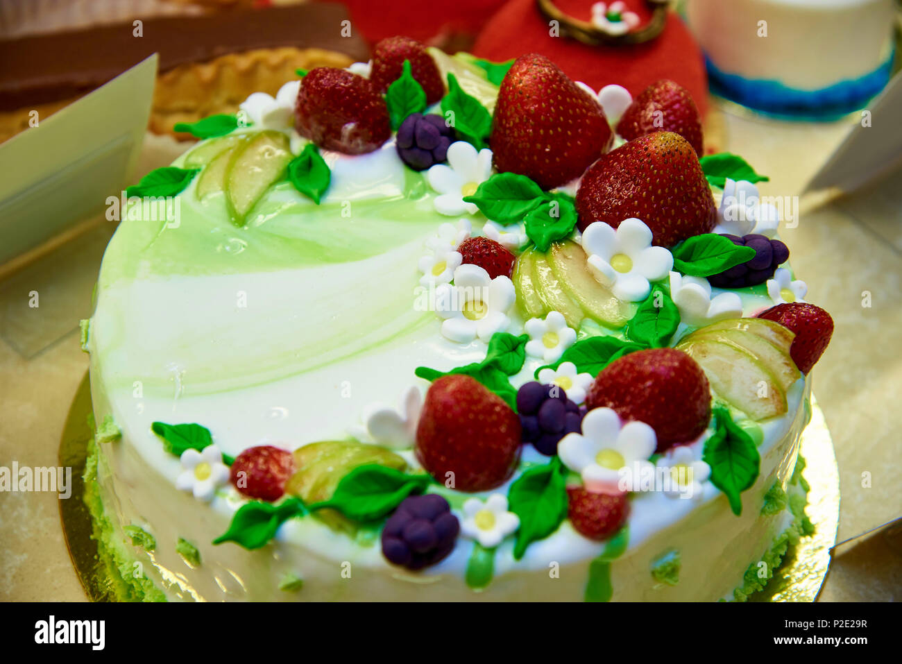 Una luminosa torta decorata con fragole e fiori di close-up nel caso di  visualizzazione Foto stock - Alamy