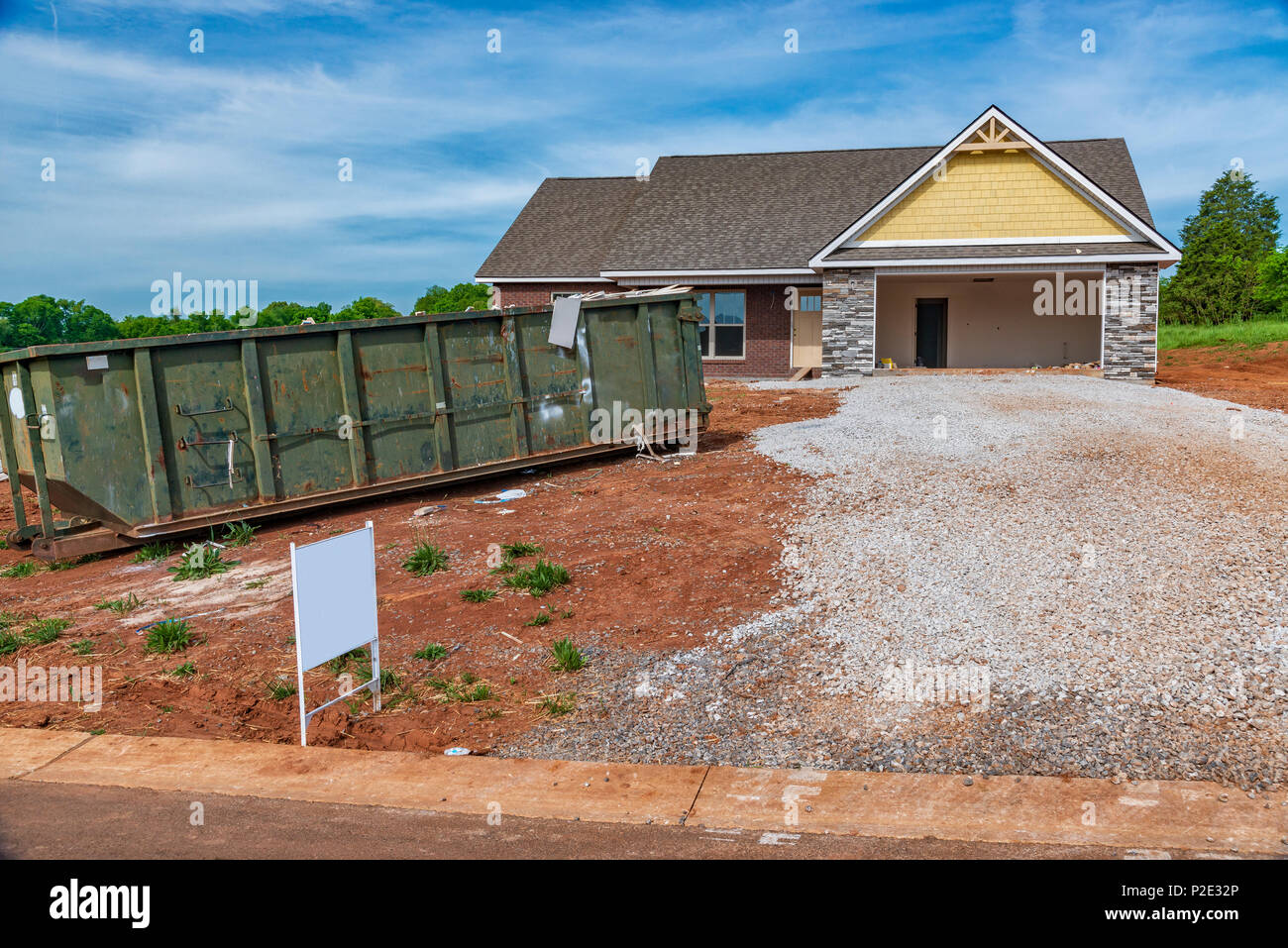 Una costruzione residenziale del sito con un dumpster di cestino accanto al viale di accesso. Foto Stock