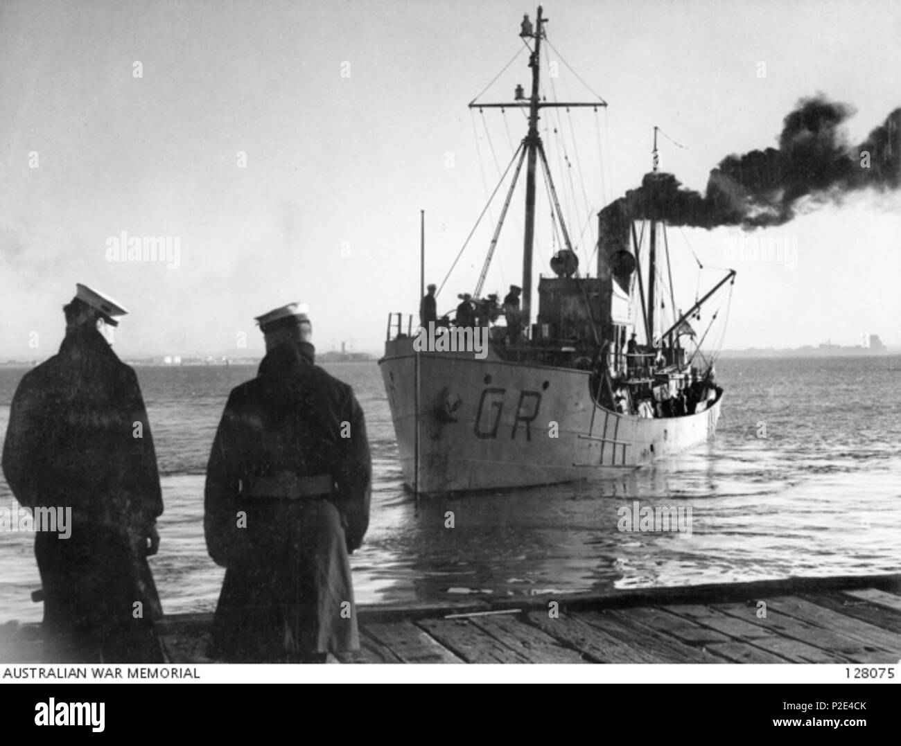 . Inglese: Il dragamine ausiliarie HMAS Goorangai venendo per attraccare ad una banchina in Port Philip, Victoria, mentre due marinai a guardare. AWM didascalia: 'dragamine ausiliarie, H.M.A.S. "GOORANGAI', che si sono scontrate con il liner costiere 'DUNTROON', in Port Phillip Bay, 1940-11-20, E AFFONDATA IMMEDIATAMENTE CON LA PERDITA DEL SUO pieno complemento di venti-quattro ufficiali e uomini" . 1940. 25 sconosciuto HMAS Goorangai ormeggio Foto Stock