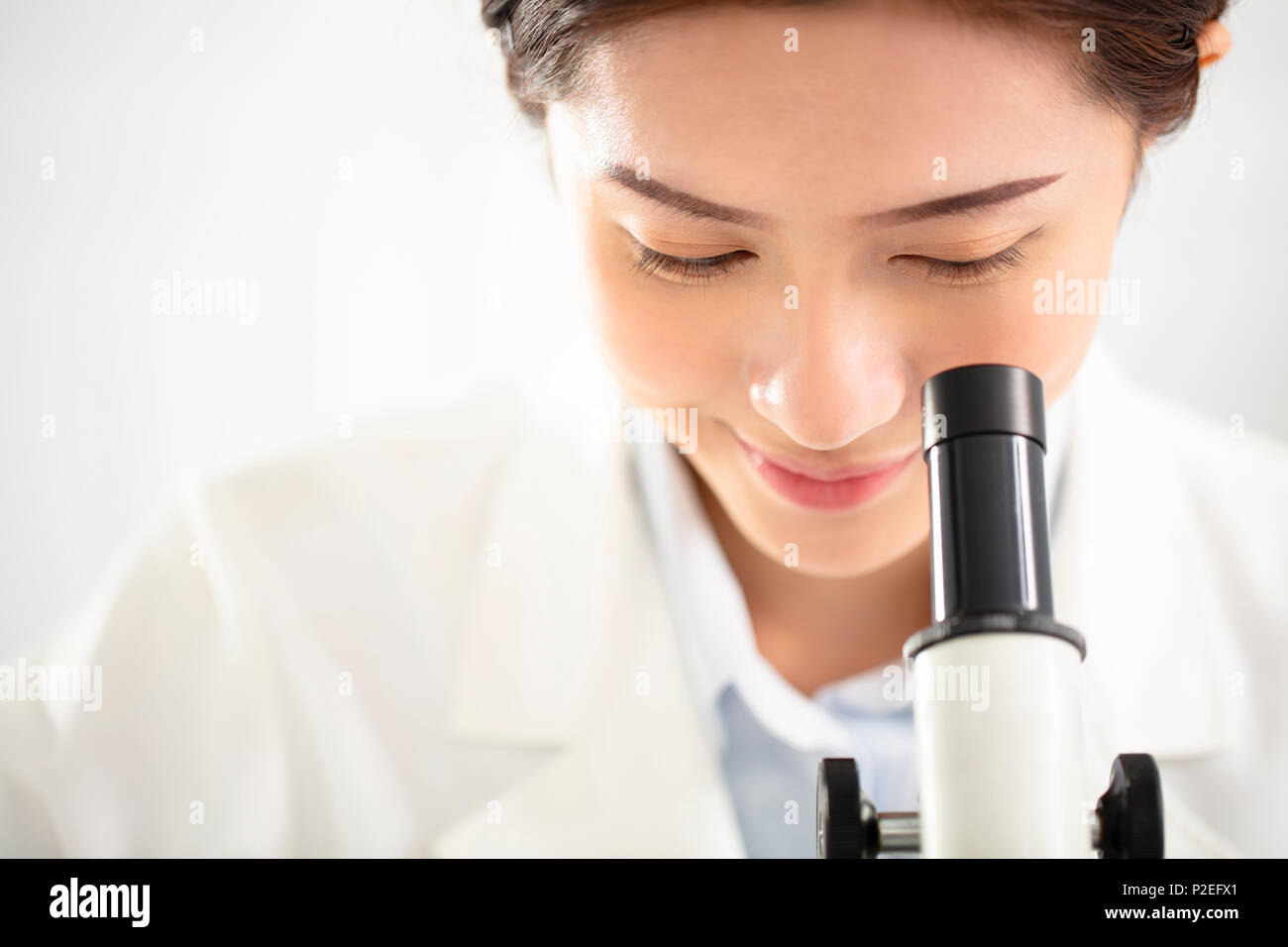 Femmina o medico ricercatore scientifico guardando il microscopio Foto Stock