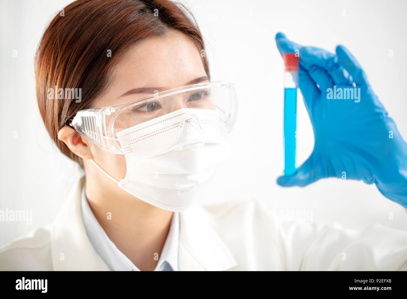 Asian donna scienziato guardando al tubo di prova Foto Stock