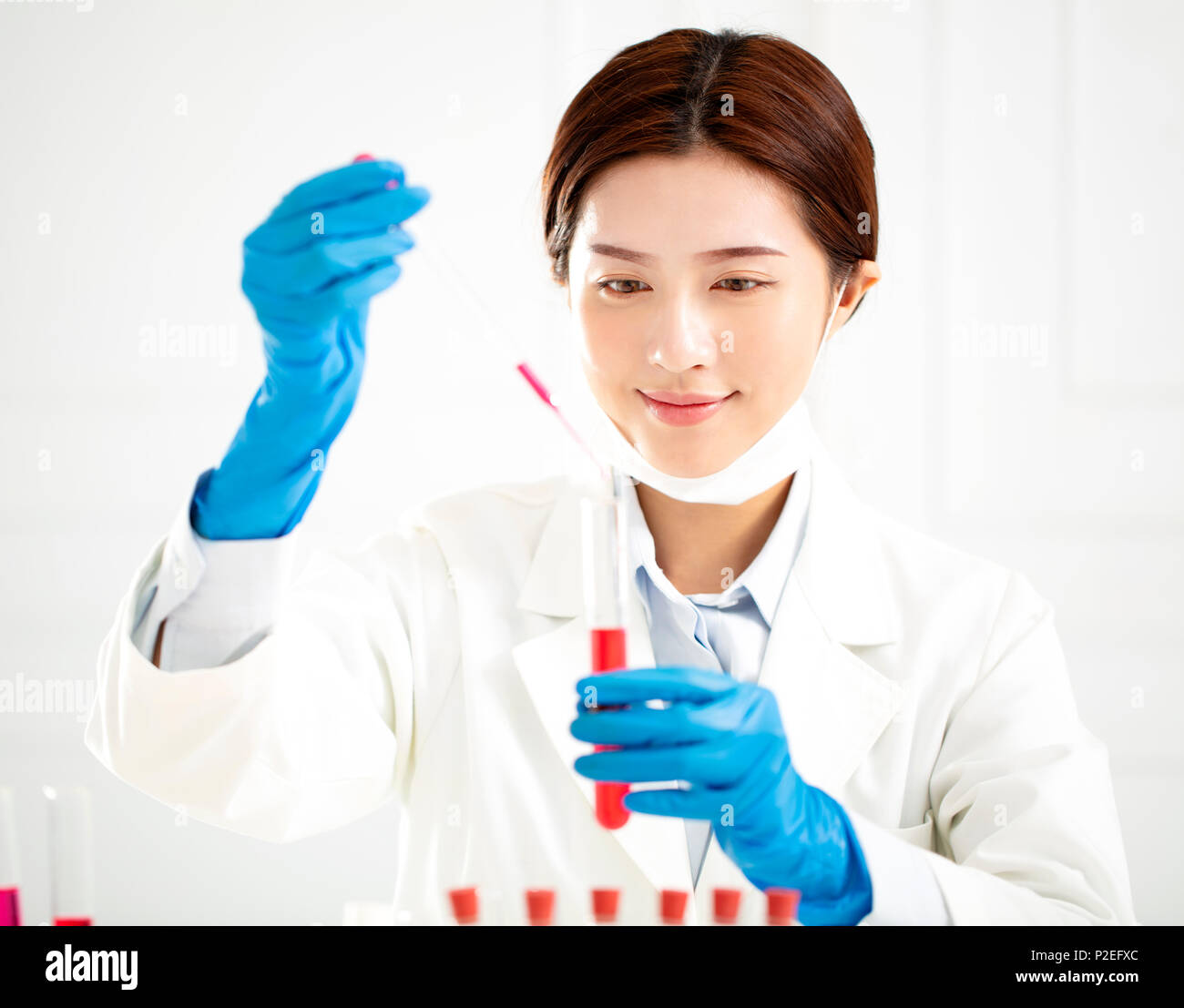 Asian donna scienziato guardando al tubo di prova Foto Stock
