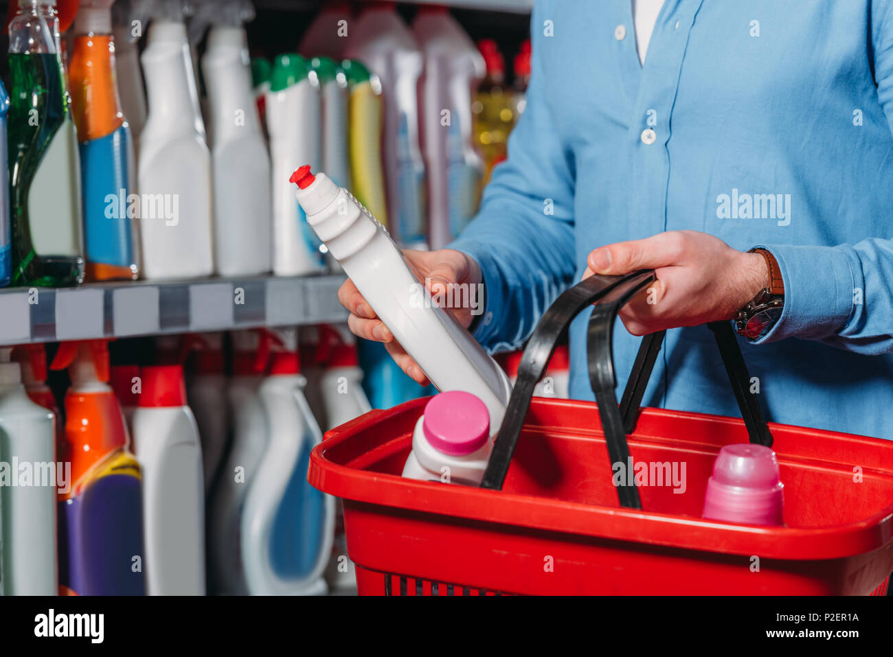 Vista parziale di shopper mettendo il detergente nel carrello nel supermercato Foto Stock