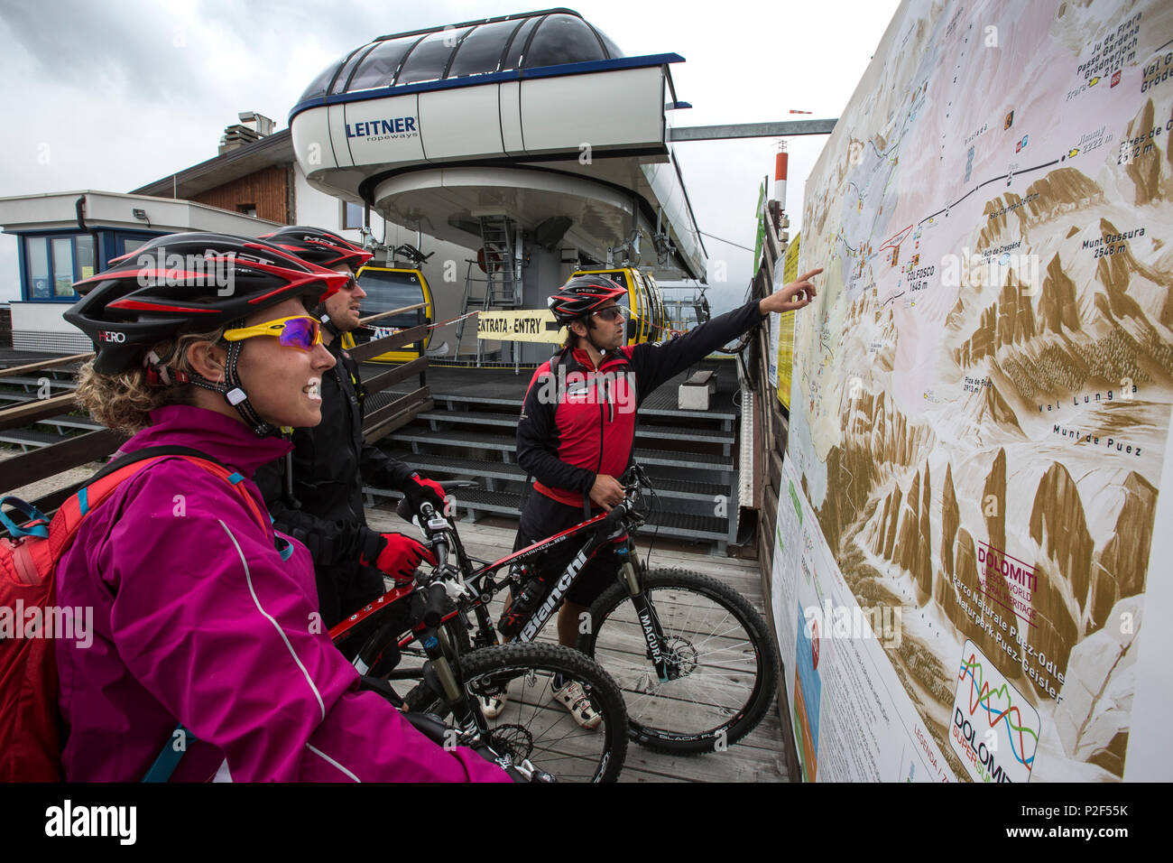 Mountain bikers guardando una mappa ambientale presso la stazione a monte Col Alt, Corvara, Trentino Alto Adige, Italia Foto Stock