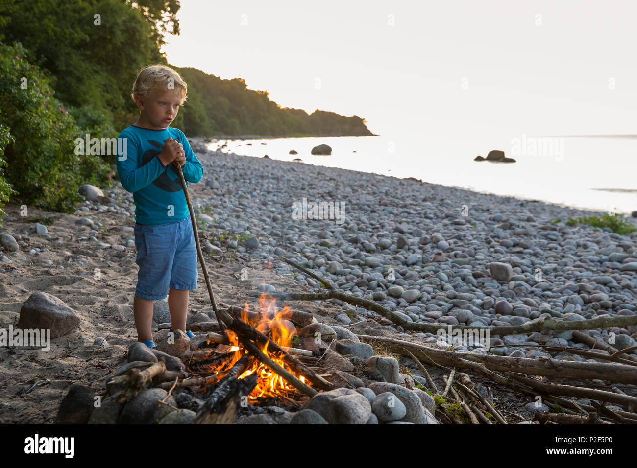 Il ragazzo, 5 anni, stando in piedi vicino al fuoco, bambino, avventura, Mar Baltico, Signor, Bornholm, vicino Gudhjem, Danimarca, Europa Foto Stock
