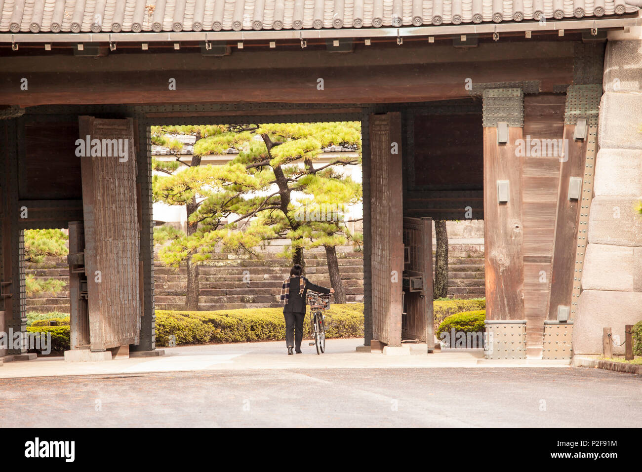 Signora con bicicletta passando Hirakawamon porta del Palazzo Imperiale, Chiyoda-ku, Tokyo, Giappone Foto Stock