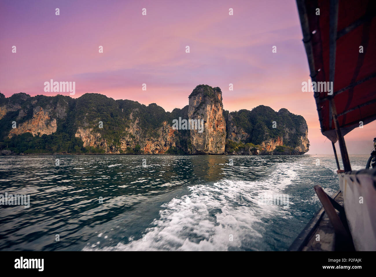 La crociera in barca dalla coda lunga con vista delle isole tropicali a Rosa tramonto nel Mare delle Andamane, Thailandia Foto Stock