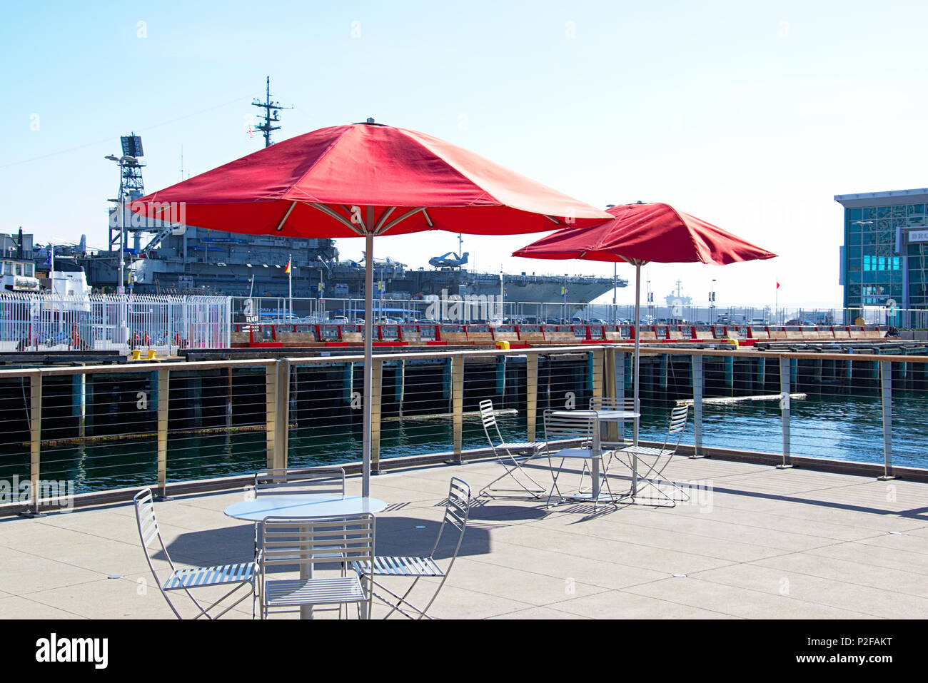 Ombrellone rosso all'esterno eatery con il bianco e i tavoli e le sedie in prossimità di un molo Foto Stock