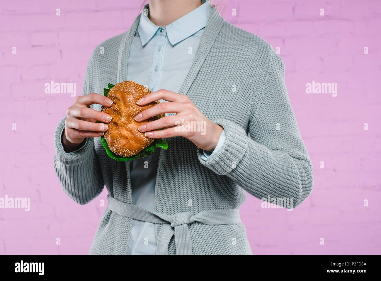 Ritagliato colpo di donna in maglione e camicia di contenimento burger gustoso Foto Stock
