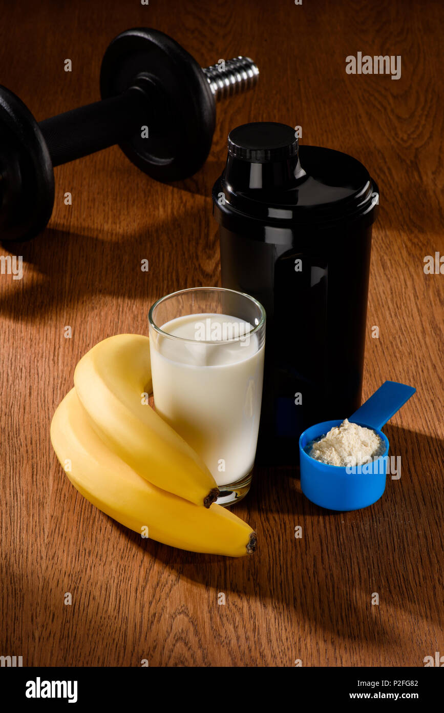 Protein Shake con il manubrio e le banane su una superficie di legno Foto Stock
