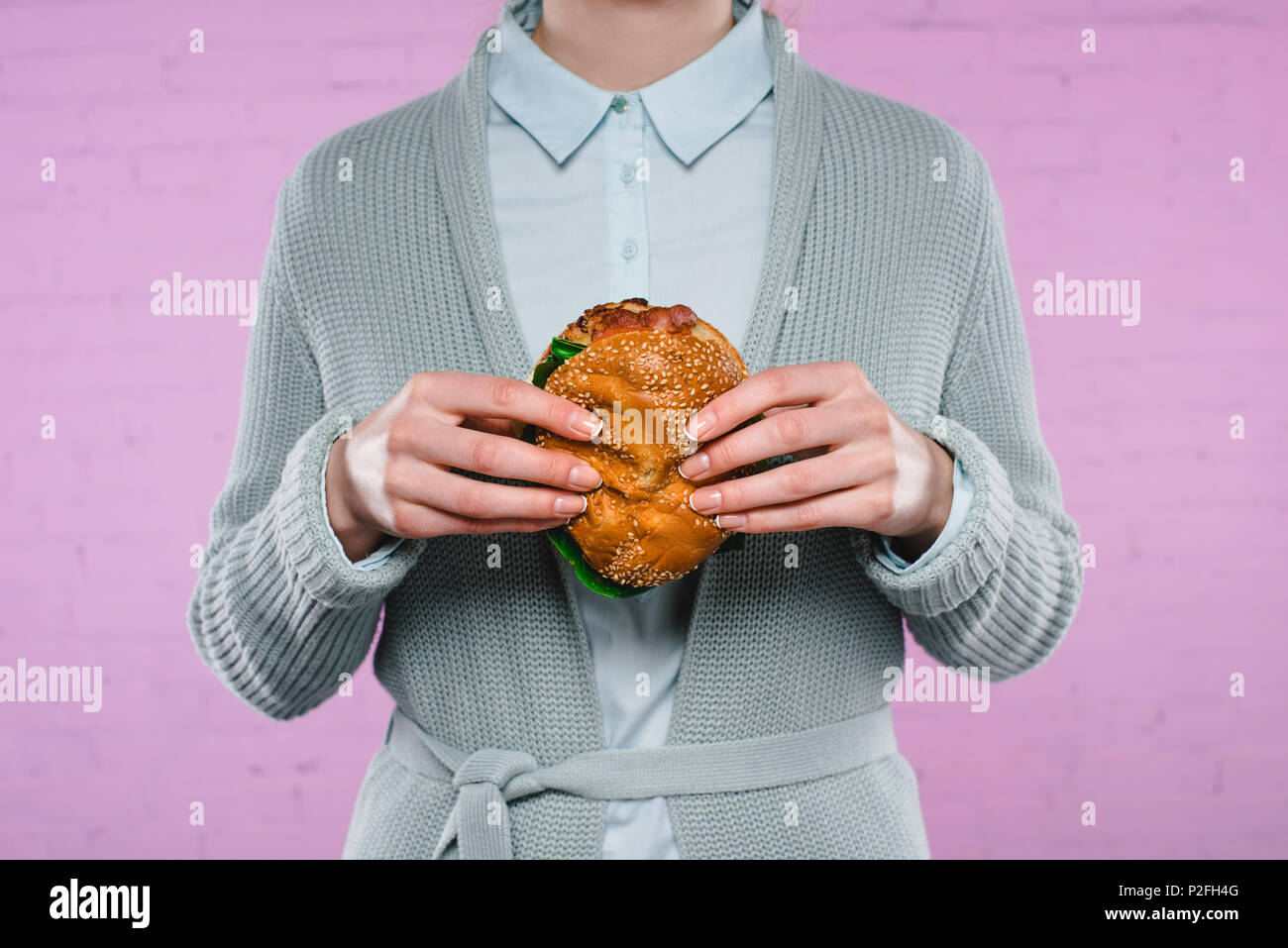 Ritagliato colpo di donna in maglione e camicia azienda burger Foto Stock