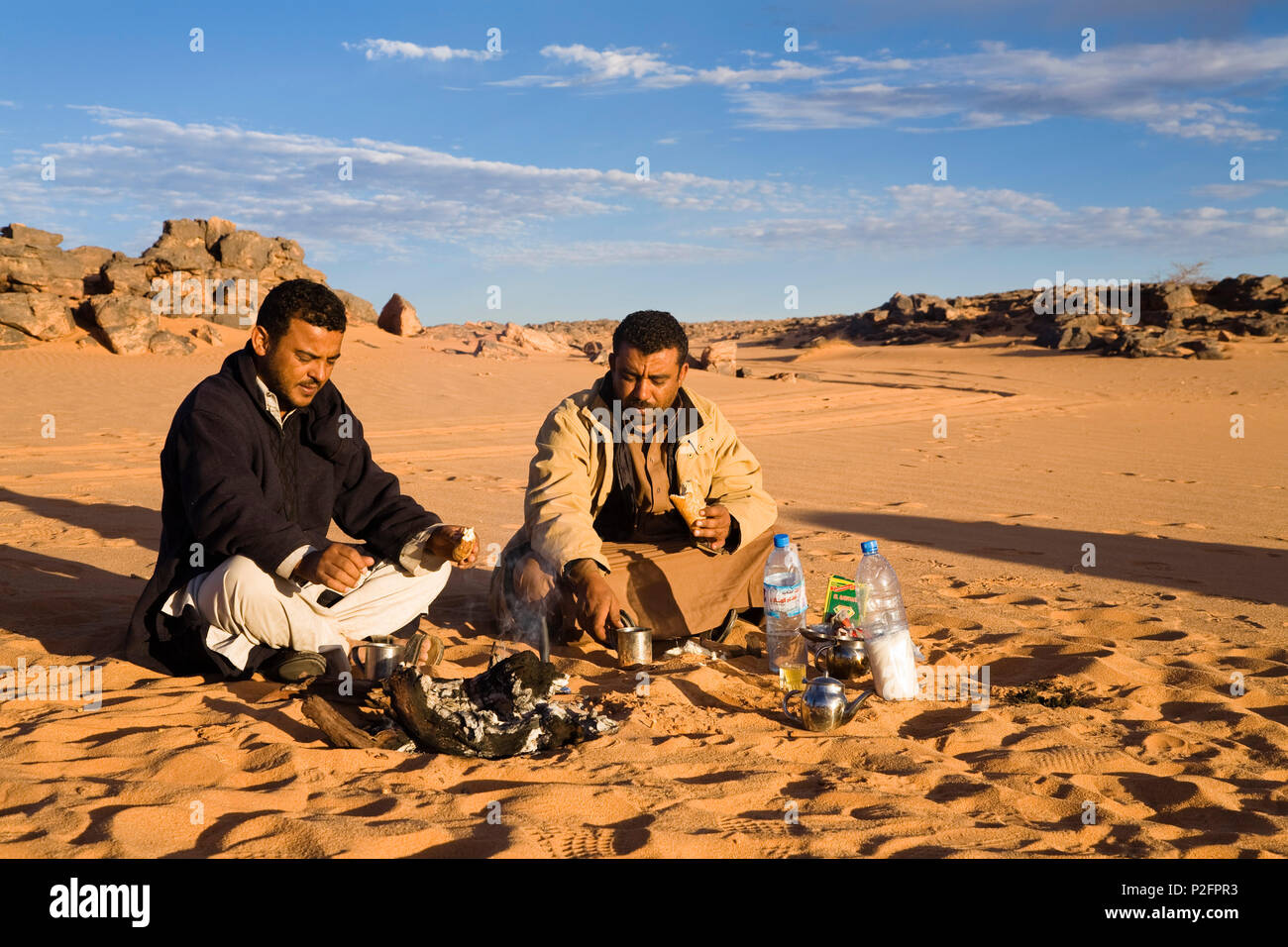 Beduins avente colazione al falò, Akakus montagne, Libia, Africa Foto Stock