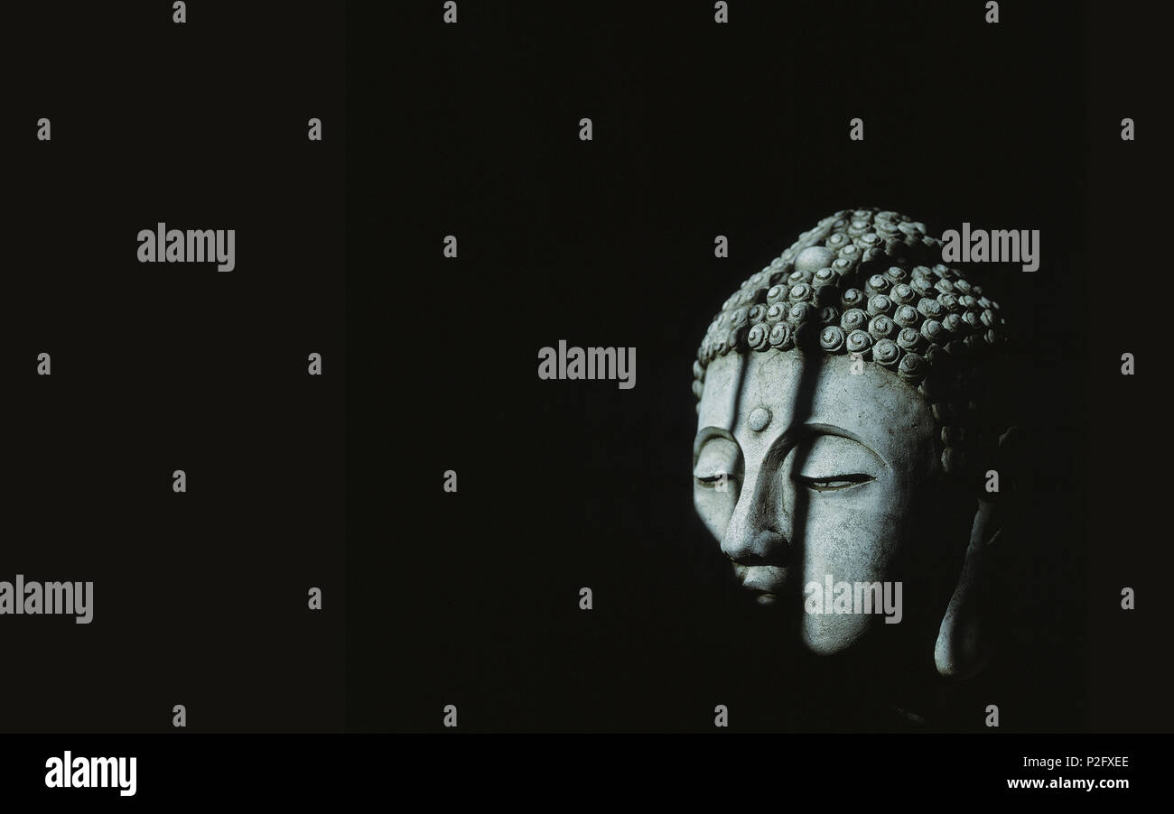 Buddha in pietra volto rigato di ombre Foto Stock