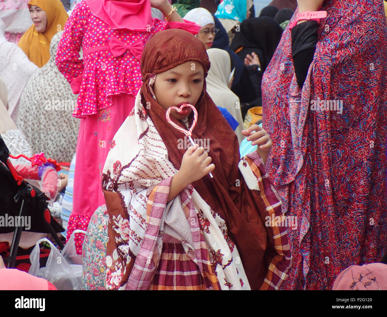 Quezon City, Filippine. Il 15 giugno 2018. Una ragazzina musulmana di mangiare una a forma di cuore ad candy. Durante l'Eid al-Fitr celebrazione in Quezon City. Credito: Sherbien Dacalanio / Alamy News live Foto Stock