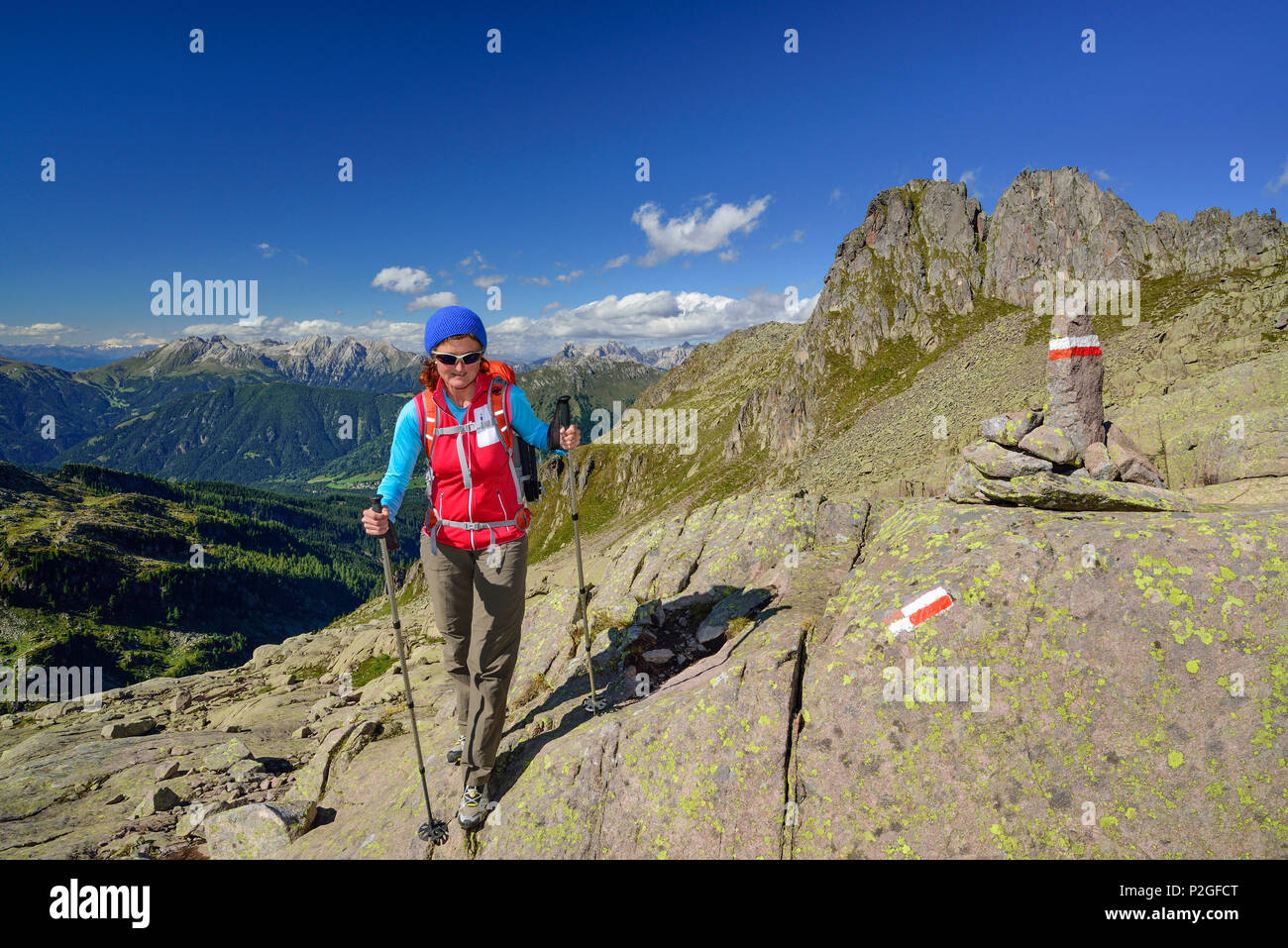Donna che cammina lungo il sentiero con segnavia e Latemar gamma in background, Trans-Lagorai, Lagorai, Dolomiti, Patrimonio Mondiale H Foto Stock