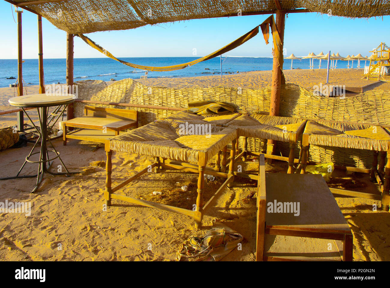 Vecchia spiaggia abbandonate mobili su un vuoto seashore contro uno sfondo di sabbia gialla e blu del cielo. Gettato, cose inutili. Vacanze, turismo. Foto Stock