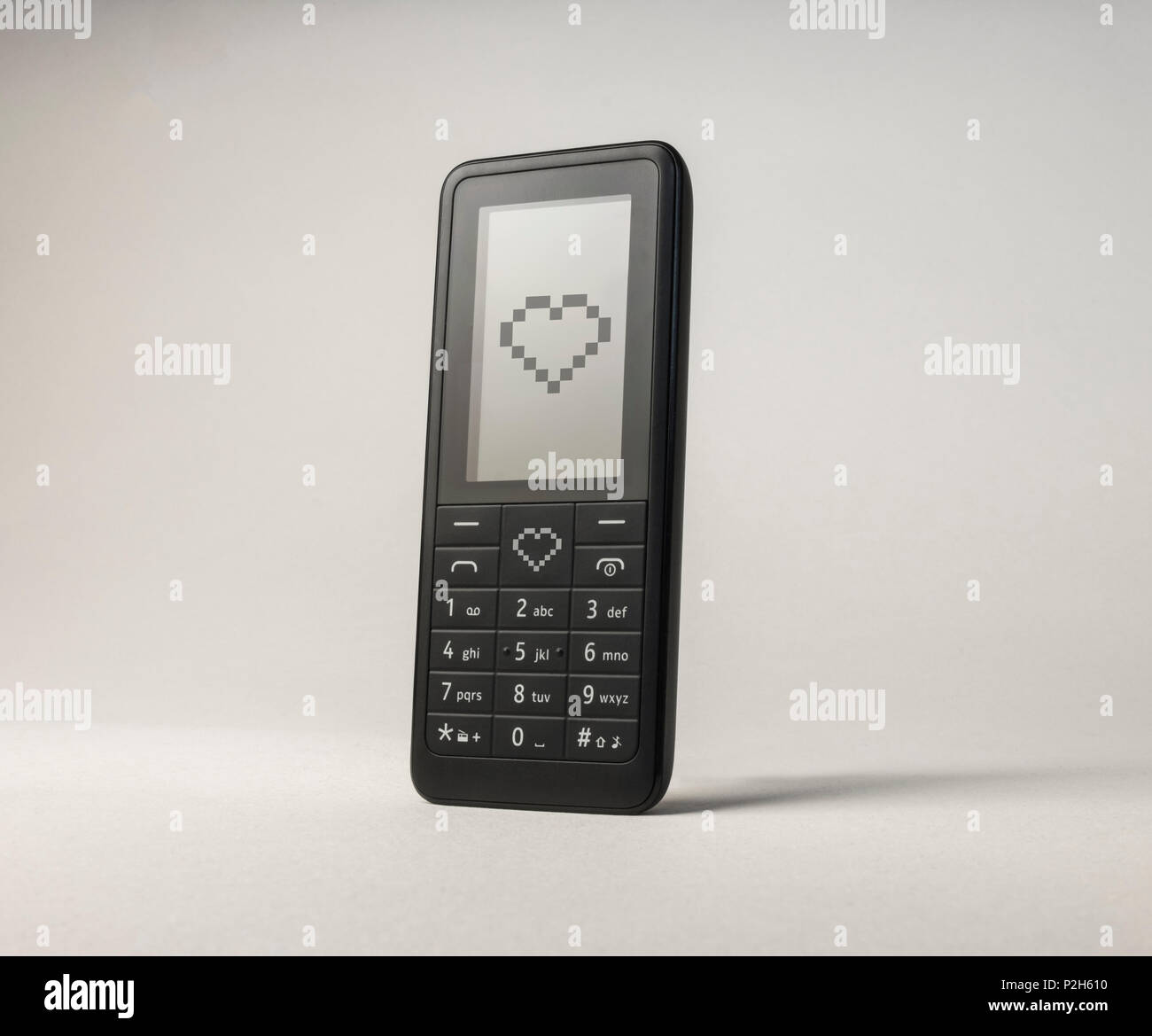 Telefono cellulare invio di cuore l'amore. Dispositivo portatile di comunicazione. Il giorno di San Valentino messaggio di testo Foto Stock
