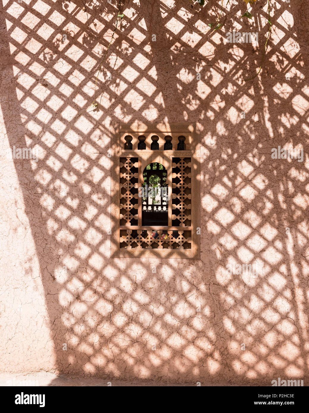 Un gioco di luci e di ombre attraverso una finestra marocchino set di frame in incrinato muri di terra di Berber Lodge Foto Stock