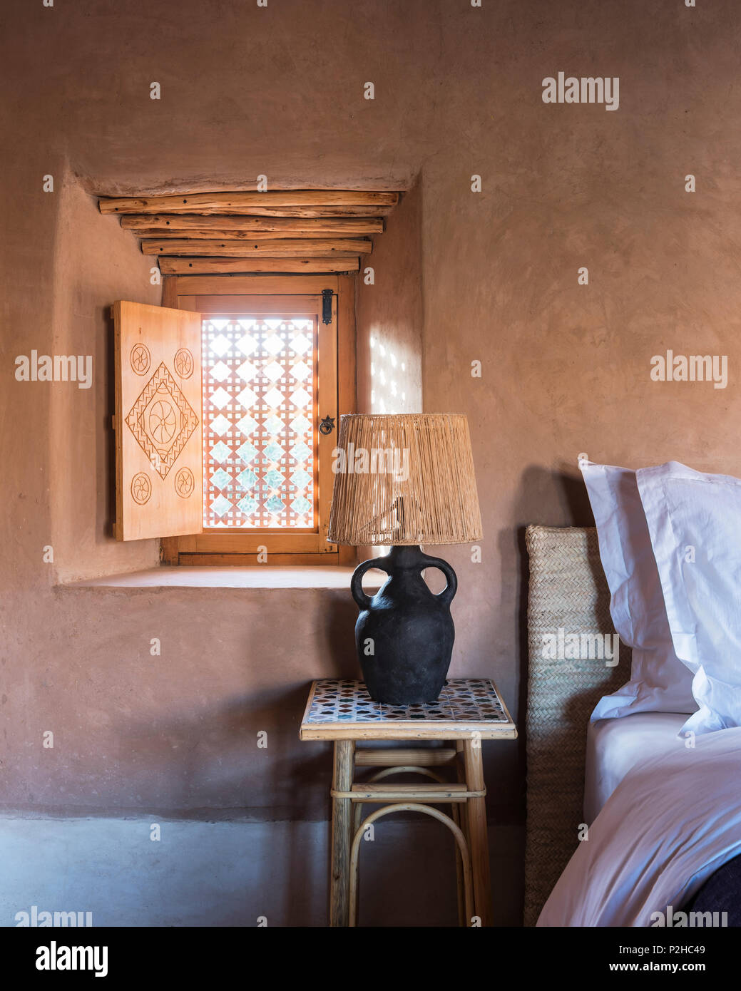 Charlotte Perriand lampada in camera da letto con muri di terra, pavimento in terracotta e tradizionali Berbere soffitto in legno Foto Stock