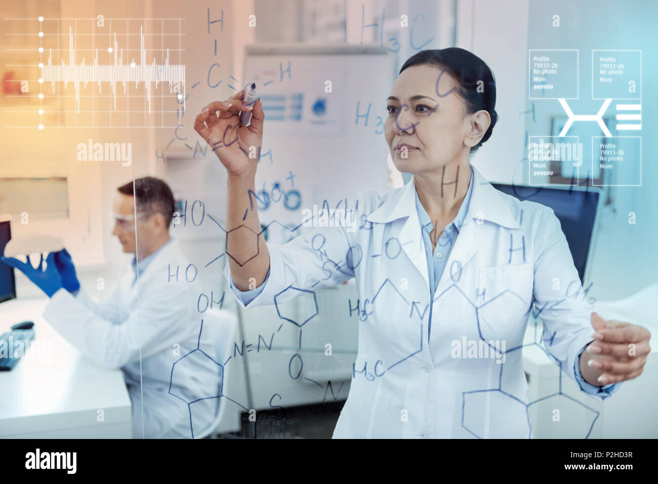 Calma farmacia cercando concentrati durante la scrittura sul pannello trasparente Foto Stock