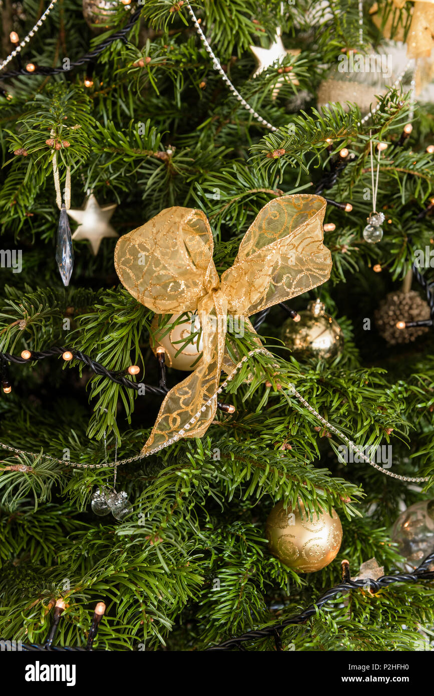 Baubles, stelle, luci fairy e archi adornano un albero di natale Foto Stock