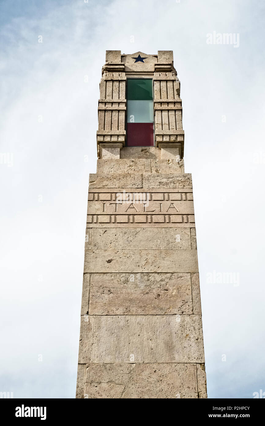 Lucca, Toscana, Italia. Un epoca fascista monumento sormontato dalla bandiera italiana e i fasces, il romano antico simbolo di potere Foto Stock