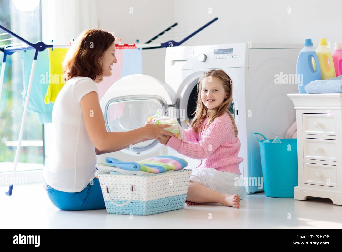 Madre e bambini nella stanza lavanderia con lavatrice o asciugatrice.  Incombenze familiari. Moderni dispositivi domestici e di detersivo di  lavaggio in bianco sunny hom Foto stock - Alamy