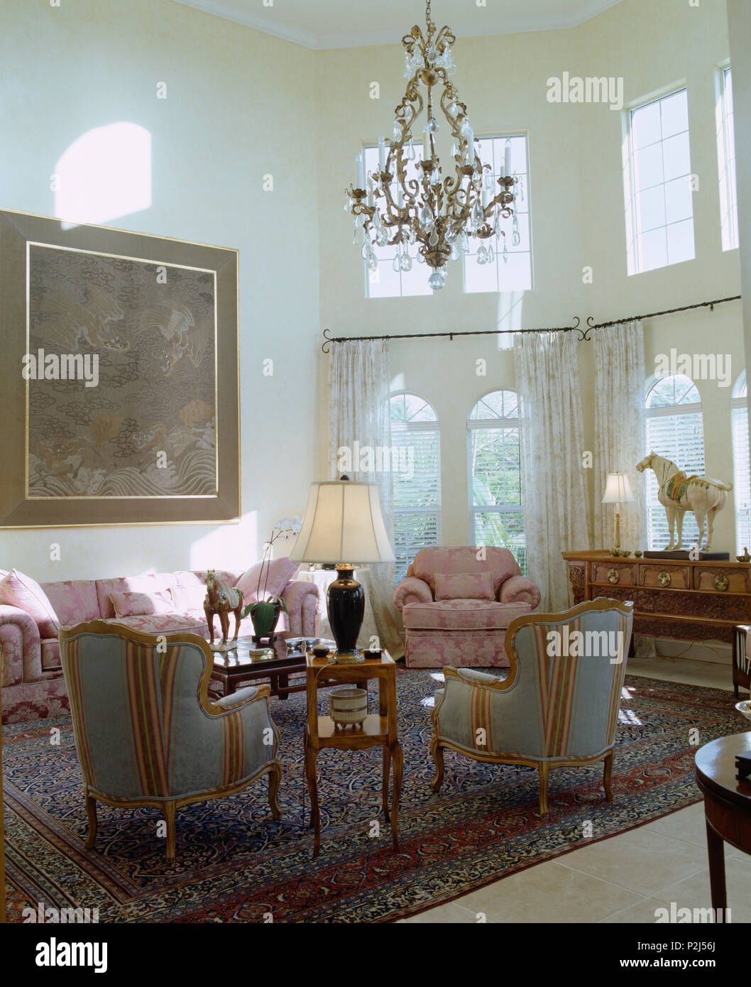 Poltrone e divani rosa sul tappeto in altezza doppia stanza di seduta Foto Stock