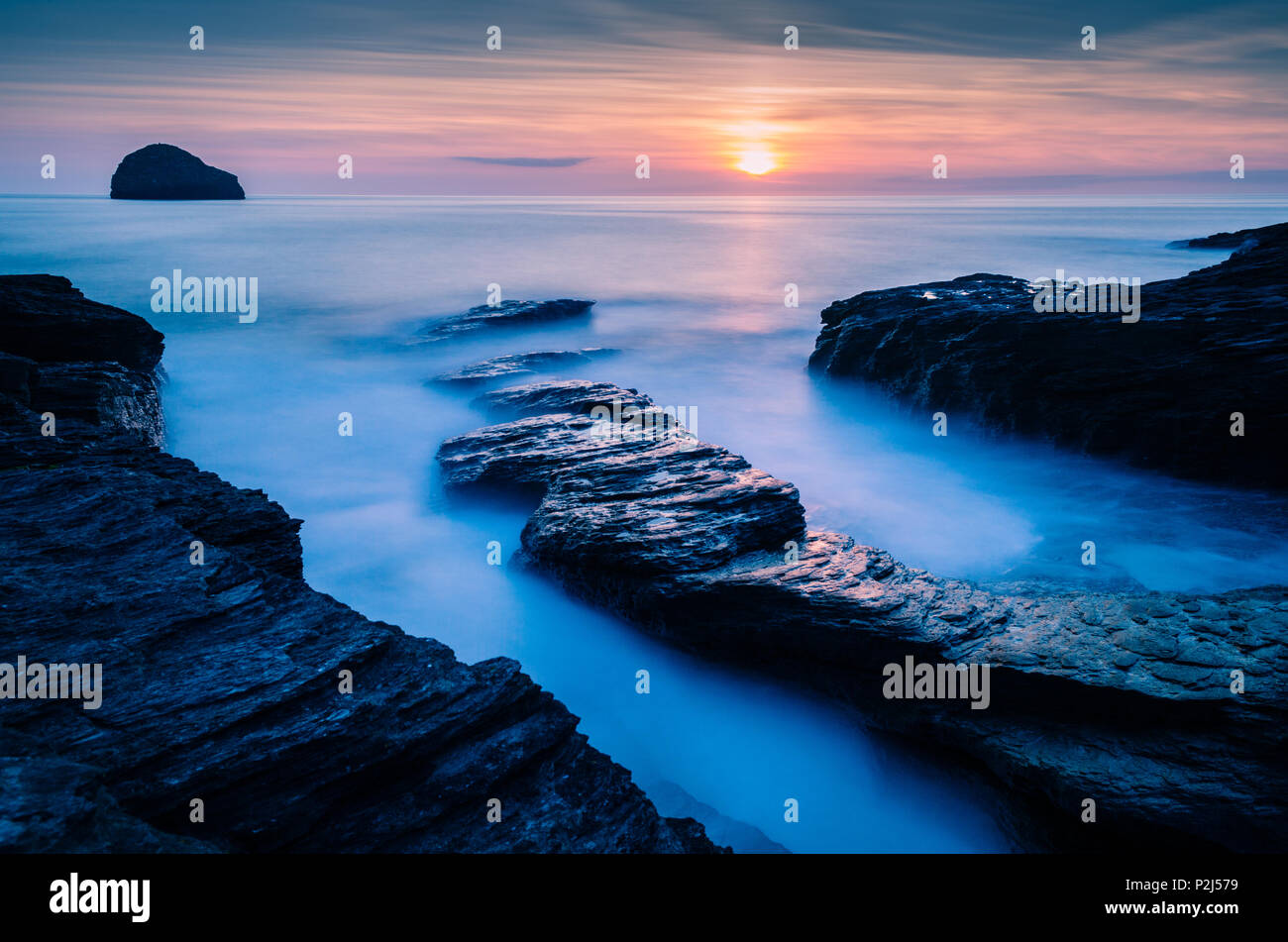 Trebarwith Strand tramonto con cielo arancione leader di rocce e Misty Waves Foto Stock