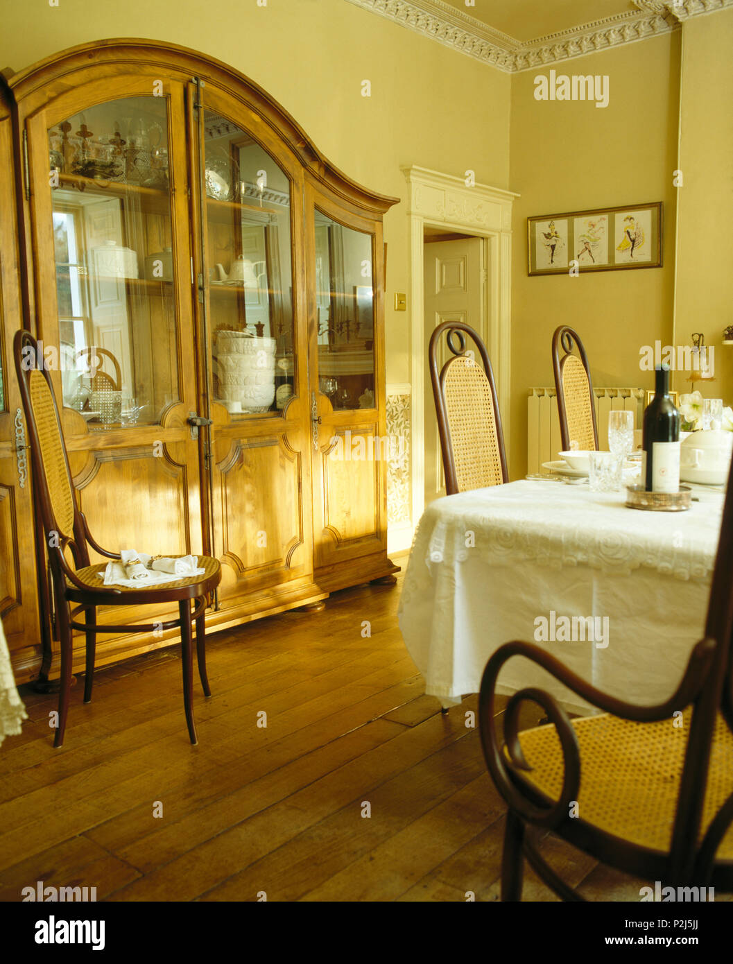 Gran parte anteriore in vetro antique dresser in sala da pranzo con pavimento in legno e sedie Bentwood Foto Stock