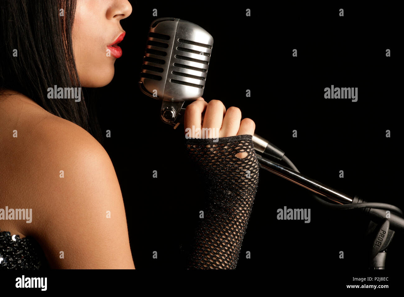 Giovane donna cantare in un microfono Foto Stock