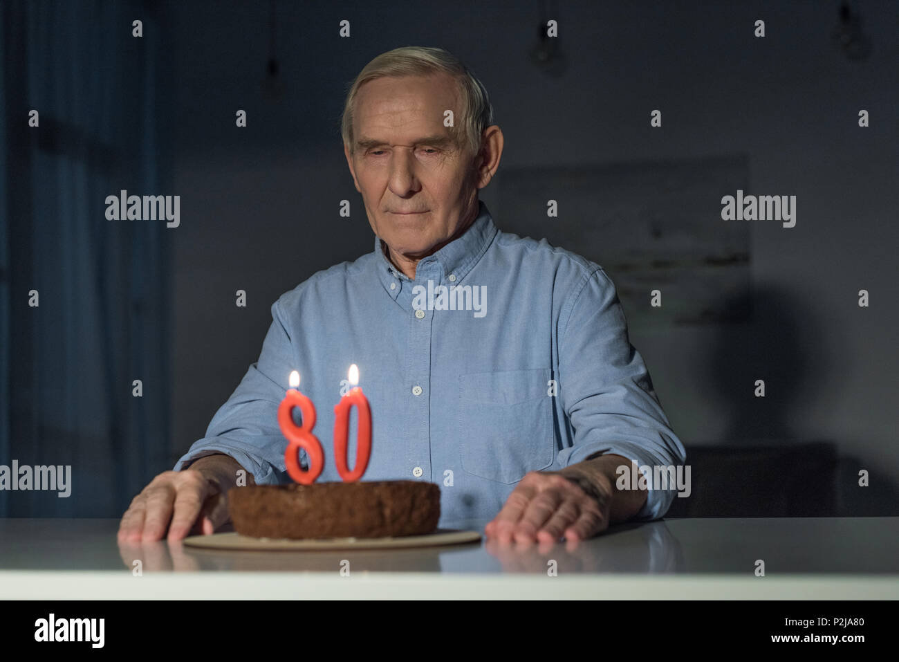 Senior lonely man celebra 80 anniversario con torta e la masterizzazione numero candele Foto Stock