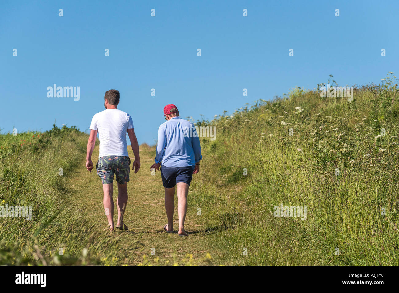 I turisti a piedi lungo un sentiero attraverso un campo sulla West pentire a Newquay in Cornovaglia. Foto Stock