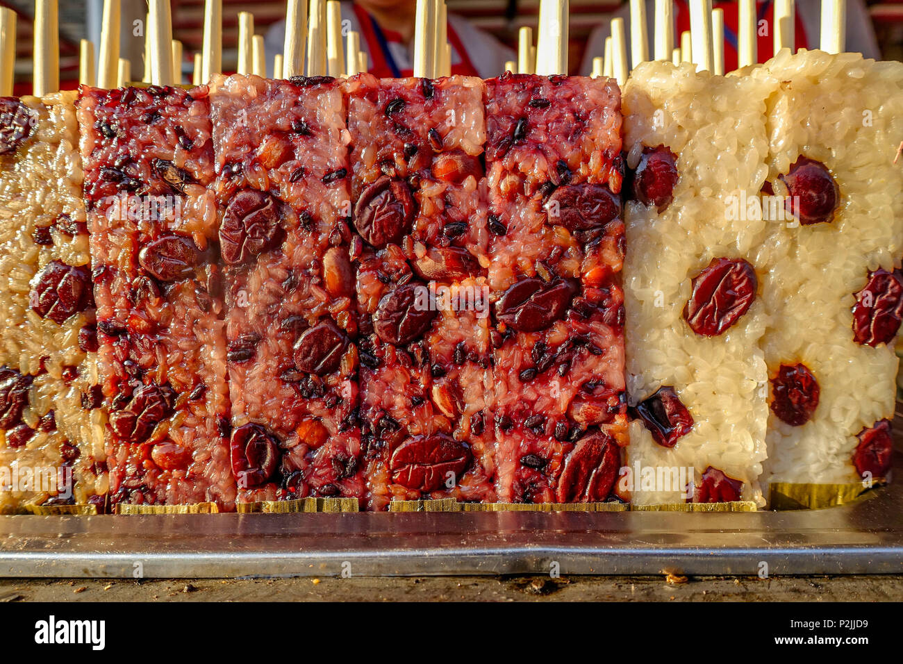 Snack Street a Beijing in Cina. Famoso Beijing street food riso glutinoso stick, cotto rettangolo viola torta di riso. Foto Stock