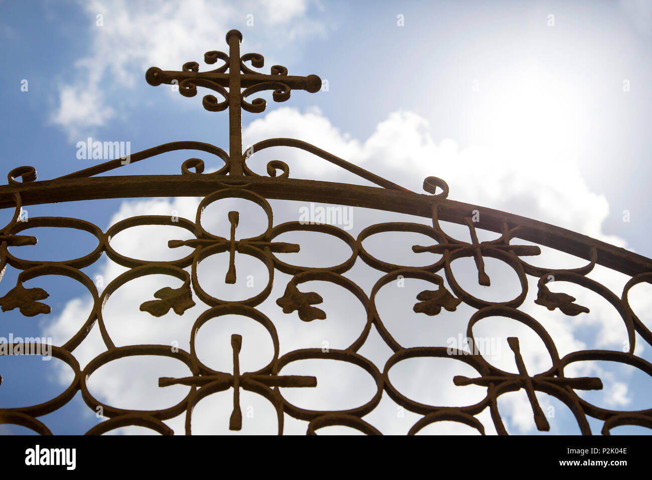 Nuvoloso estate cielo visto verso l'alto attraverso la cancellata in ferro battuto con una croce cristiana simbolo sul Santorin Foto Stock