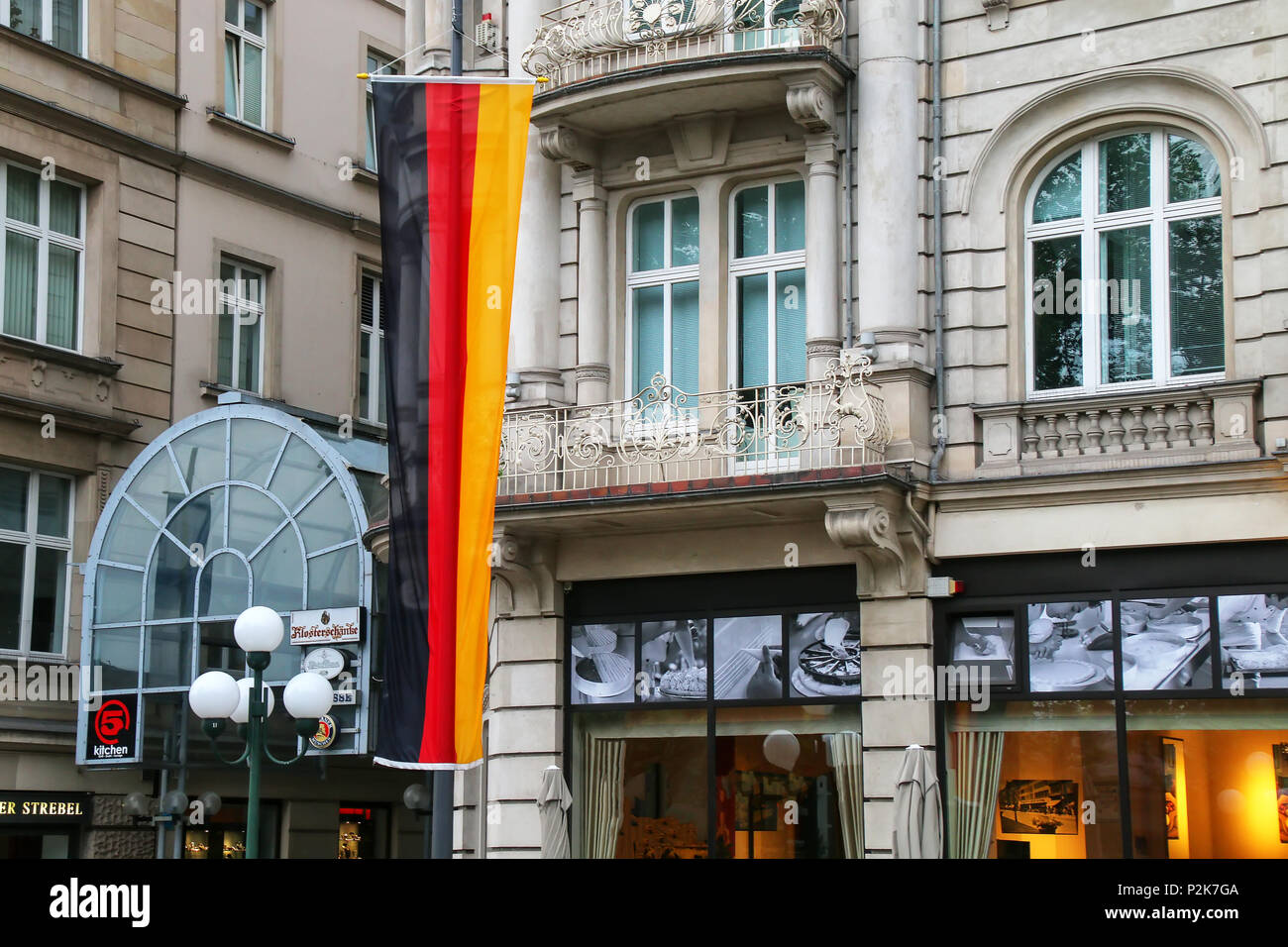 Bandiera nazionale della Germania accanto a un edificio in Wiesbaden city centre, Hesse, Germania. Wiesbaden è uno dei più antichi centri termali in Europa Foto Stock
