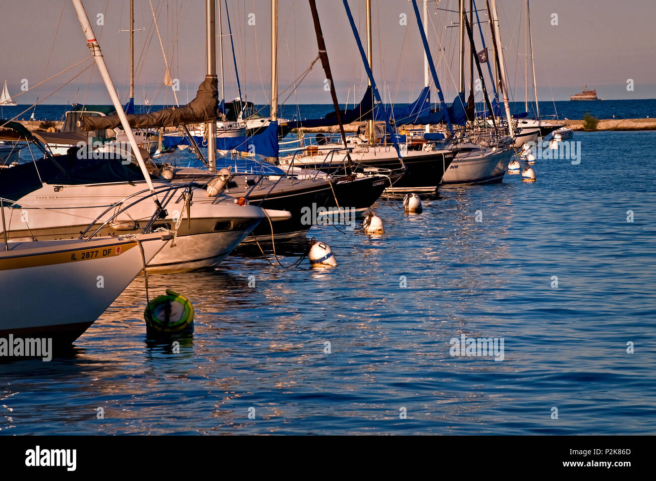 Barche a vela resto pacificamente a loro ormeggi come il sole tramonta sul porto di Burnham, Chicago dal lungolago. Foto Stock