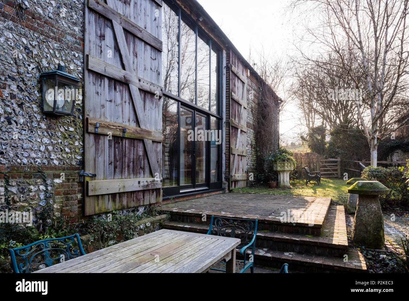 Mobili da esterno sulla terrazza di un fienile convesrion con grandi finestre e persiane di legno, Sussex Foto Stock