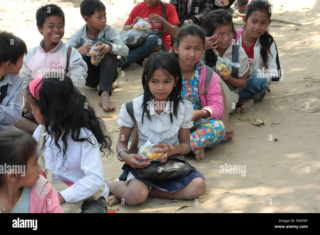 Scuola cambogiano bambini sedersi sulla terra per mangiare inaspettato considera fornita da un gruppo di finanziamento alla risma scuola locale. Foto Stock
