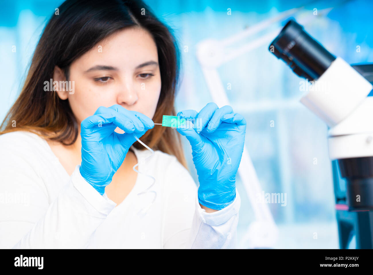 Il tecnico ragazza con dispositivo microfluidico LOC in laboratorio microbiologico Foto Stock
