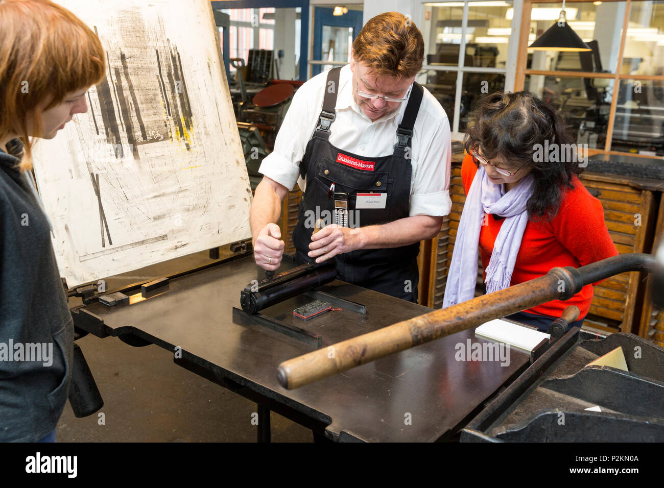 Visitatore e lavoratore stampa mediante un rullo di stampa, il Museo delle Arti di stampa Leipzig, Lipsia, Sassonia, Germania Foto Stock