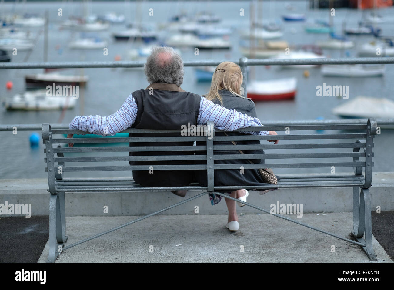 Una coppia di mezz'età seduta su una panchina in riva al mare in Falmouth, Cornwall. Foto Stock
