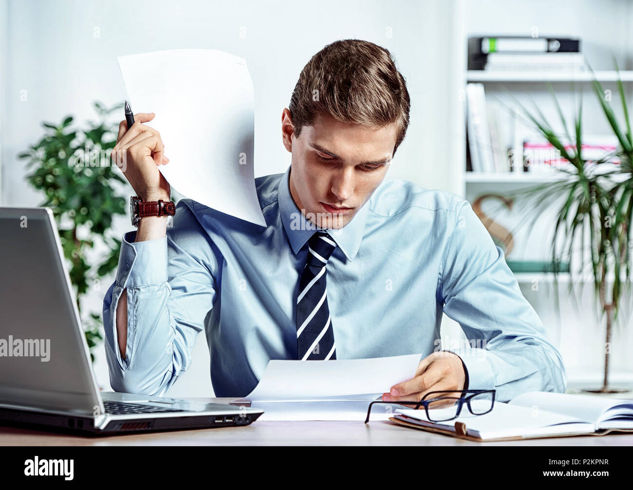 Imprenditore serio seduto alla sua scrivania la lettura di documenti. Foto di uomo di successo lavora in ufficio. Il concetto di business Foto Stock