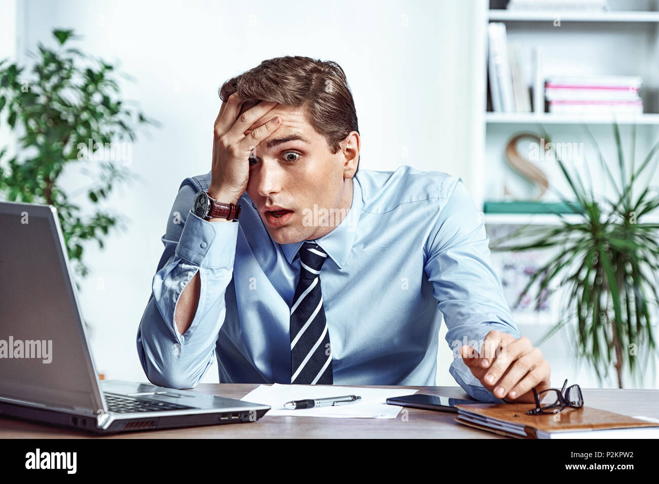 Scioccato imprenditore insoddisfatto il suo salario. Foto del giovane uomo che lavora in ufficio. Il concetto di business Foto Stock